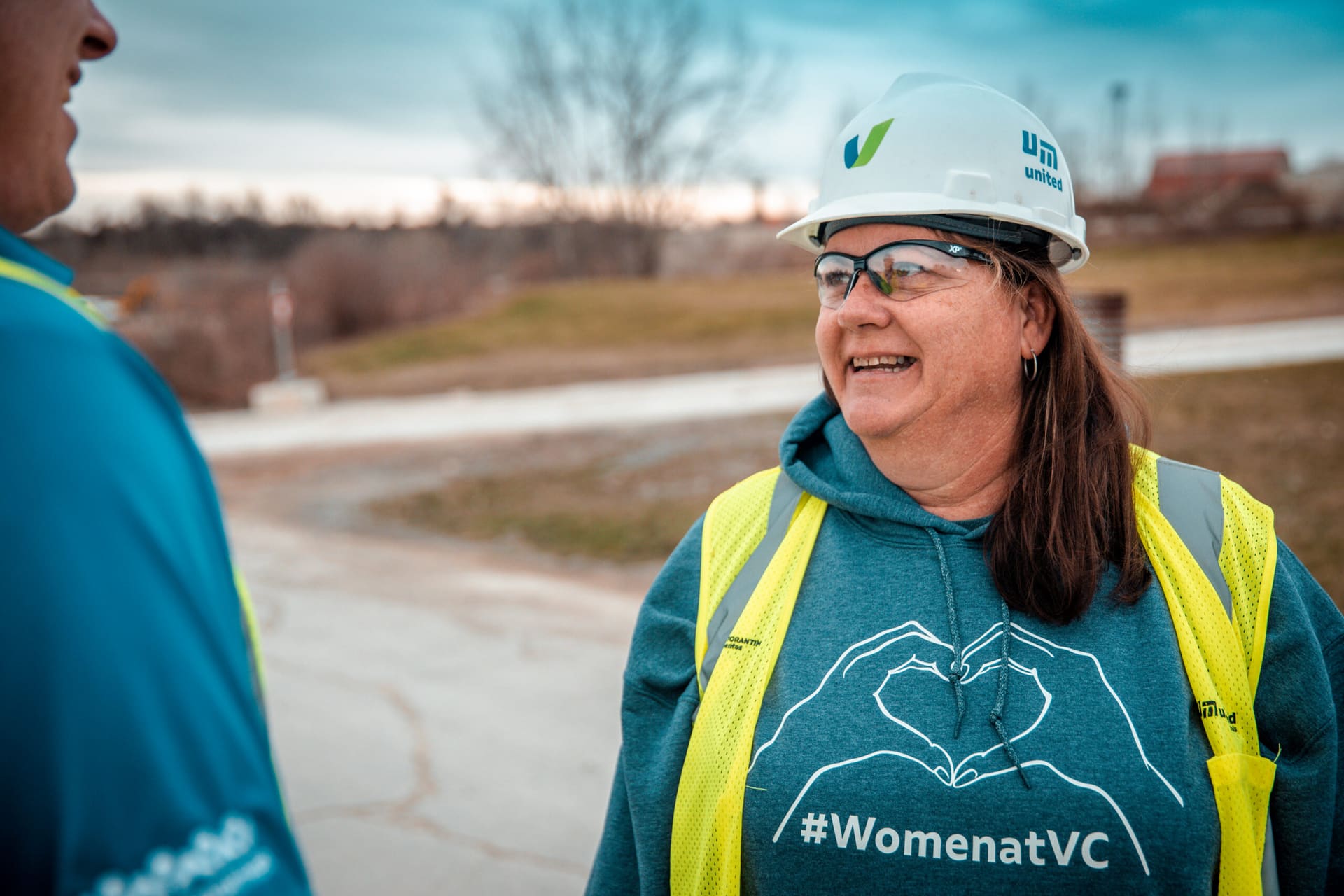 DelaySet - United Materials team member in a #WomenatVC hoodie and safety vest smiling at a plant yard