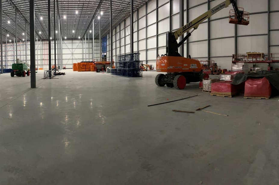 Re-Pel - wide interior of a new warehouse with a finished concrete floor and a boom lift